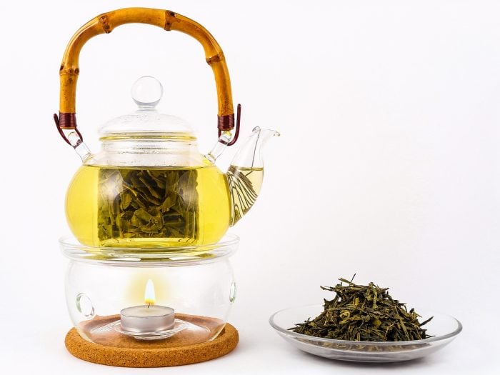 A kettle of tea and loose-leaf tea in a plate