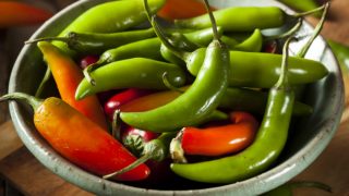 Red and green serrano peppers in a bowl