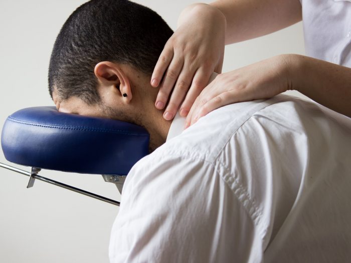 A man sitting with her head resting on a head support for neck massage