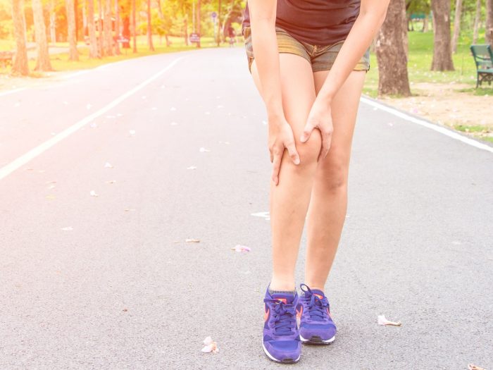 A woman holding her knee in pain