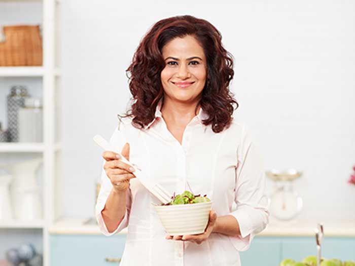 Shonali Sabherwal, Macrobiotic Nutritionist & Chef, holding a salad bowl in her hand and looking at the camera