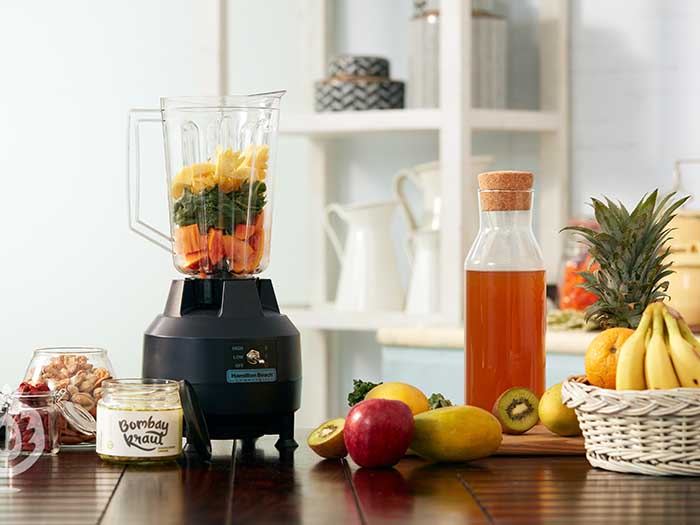 A juicer with fruits in it on a table top