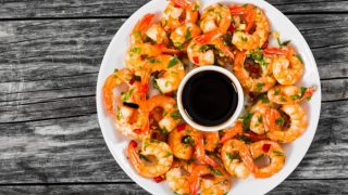 Cooked shrimp with soy sauce in a plate atop a wooden board