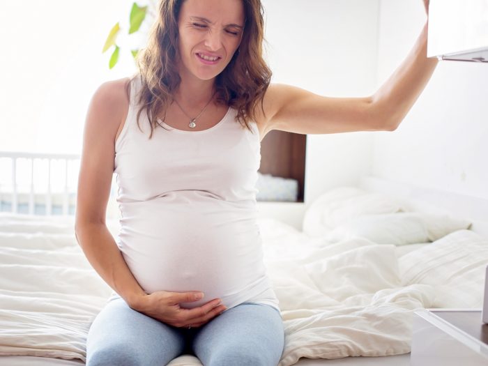 A pregnant woman grimacing and clutching her stomach