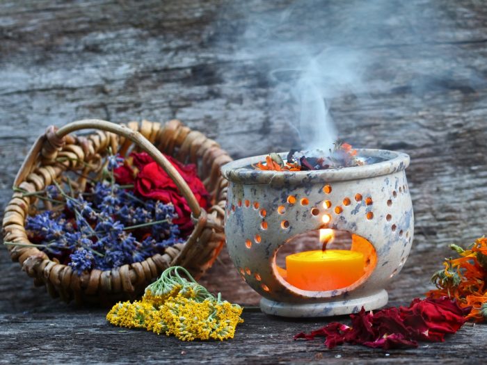 A smoking pot with flowers and a basket in the foreground with lavender leaves