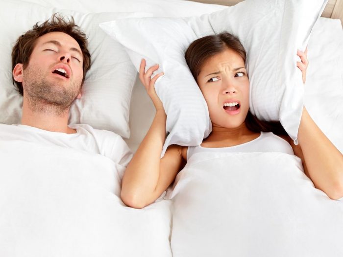 A man snoring and a woman next to him getting annoyed