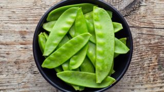 Multiple snow peas in a brown bowl
