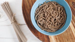 Cooked soba noodles in a bowl and dried soba noodles tied in twine
