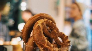 Soft, salted pretzels kept in a glass jar against a hazy background of people and lights