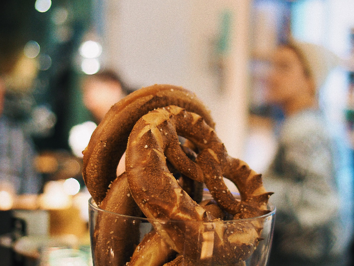 Soft, salted pretzels kept in a glass jar against a hazy background of people and lights