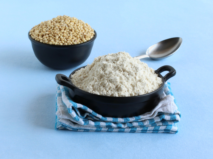 Sorghum flour in a wok, and a bowl of sorghum in the background