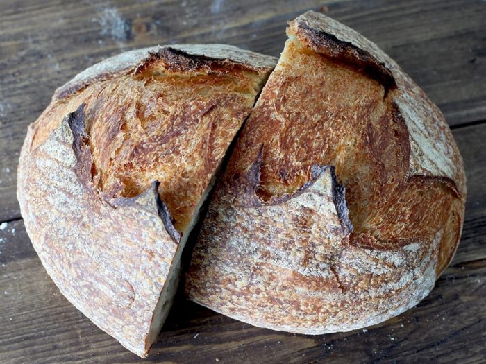 Sourdough bread sliced into 2 on a wooden table