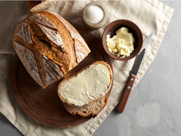 Sourdough loaf, sliced buttered toast with butter and sugar on wooden cutting board