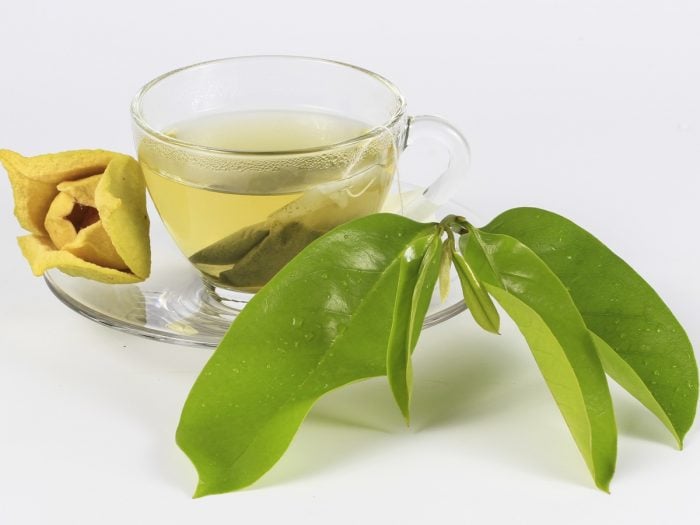 a cup of soursop tea with its leaves aside