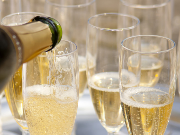 Sparkling wine is poured into a glass with other already filled glasses next to it