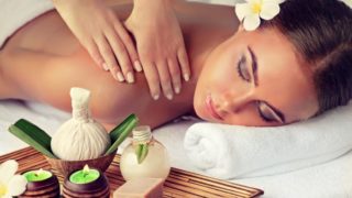 women lying front down on a bed by getting a massage