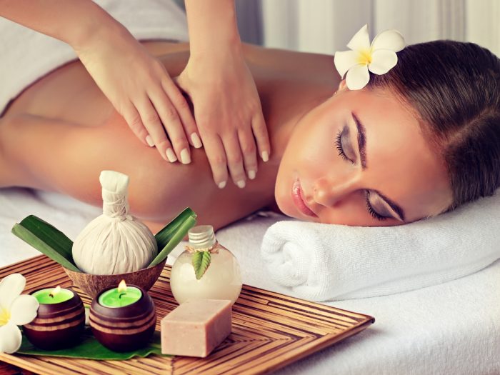 women lying front down on a bed by getting a massage