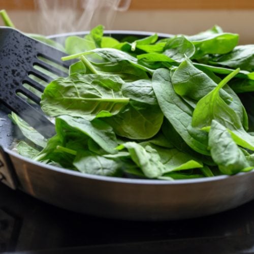 Cooking fresh spinach in a pan on the stove