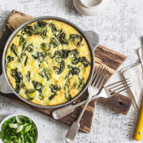 Potato and spinach frittata in a pan on a light background