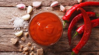 A bowl of red sauce with red chilies around it