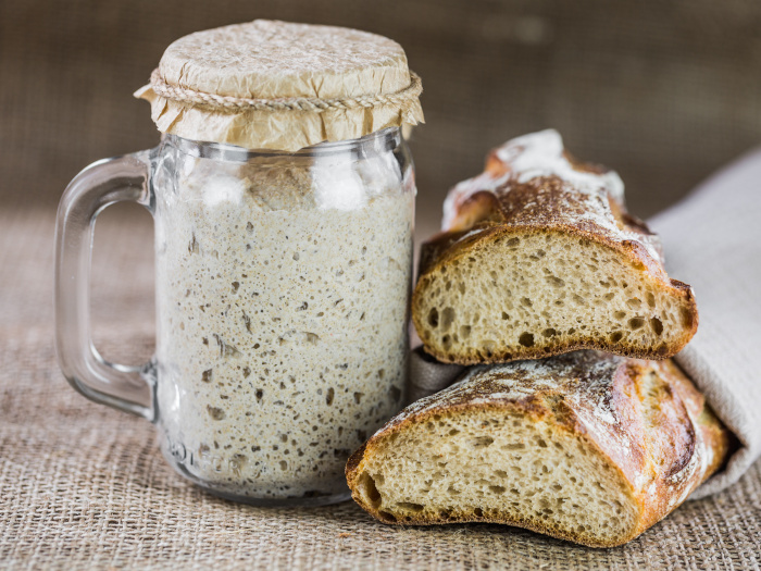 Two loaves of sourdough breads with a bottle of starter
