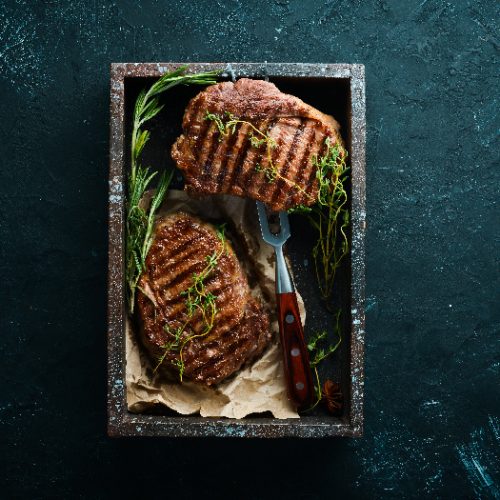 Steak fillets with rosemary and other herbs on a black serving dish