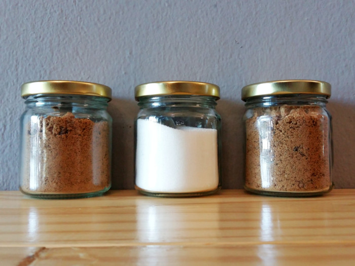 Three different types of sugar in three different jars on a table