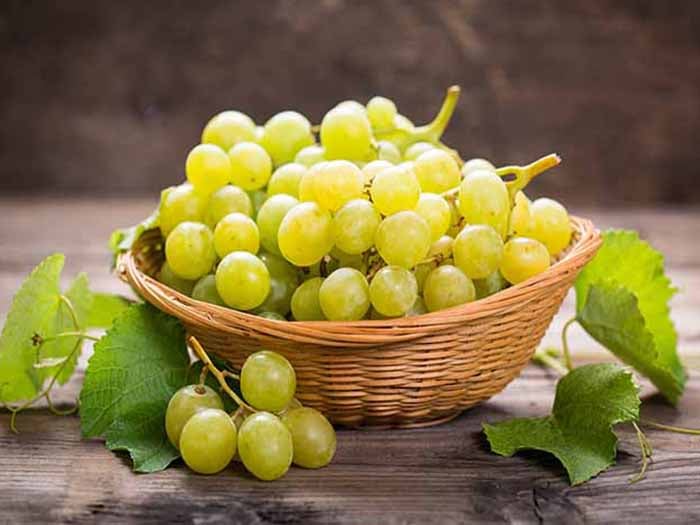 A basket of green grapes on a wooden table