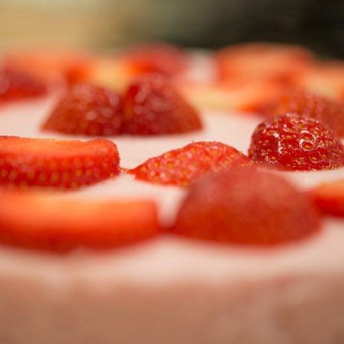 Extreme close-up of strawberries in cream.