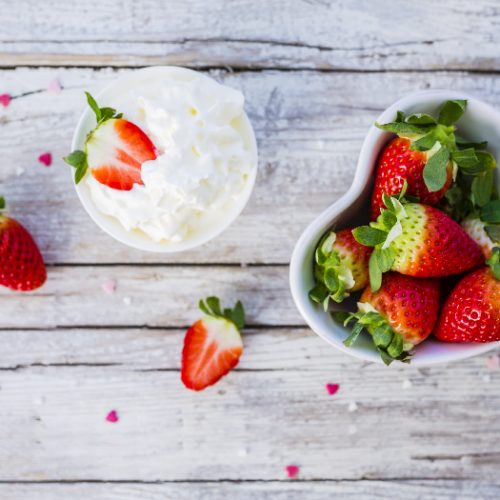 A bowl of strawberries and a bowl of cream