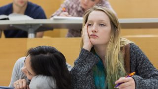 a girl looking tired sitting next to another girl with her head down
