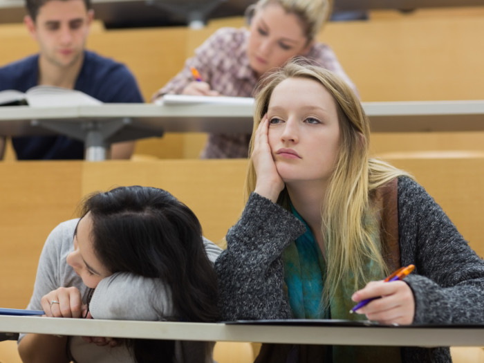 a girl looking tired sitting next to another girl with her head down