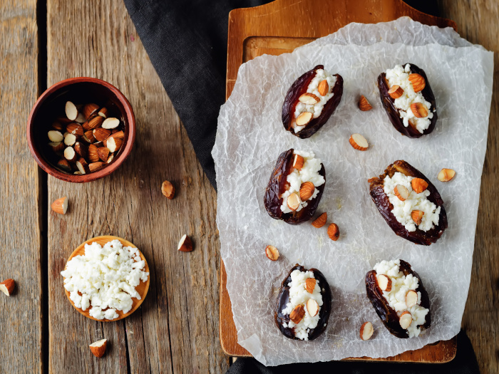 Almond and goat cheese stuffed dates on a wooden cutting board