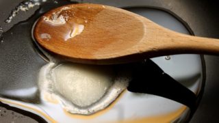 Coconut oil getting warmed on frying pan with a wooden spoon