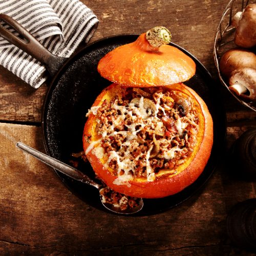 A flatlay picture of tasty autumn stuffed pumpkin with fresh mushrooms ready to serve for a seasonal dinner,