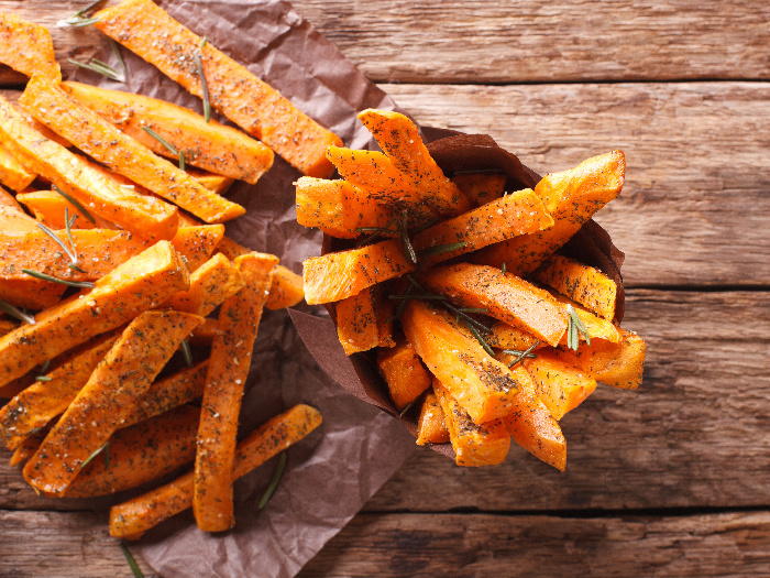 Sweet potato fries with ketchup on parchment paper and wood
