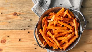 Sweet potato fries in a bowl on a napkin on a wooden table