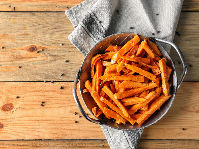 Sweet potato fries in a bowl on a napkin on a wooden table