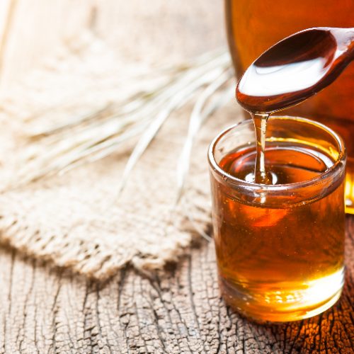 Syrup in a glass with a bottle in the background