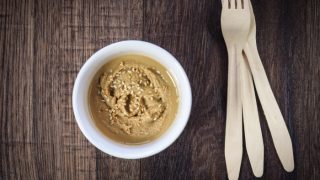 Tahini in a bowl and wooden forks on a wooden table