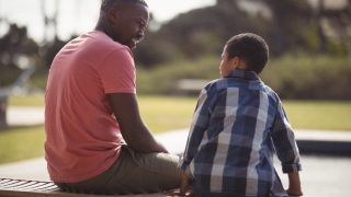 Smiling father talking to son near pool side