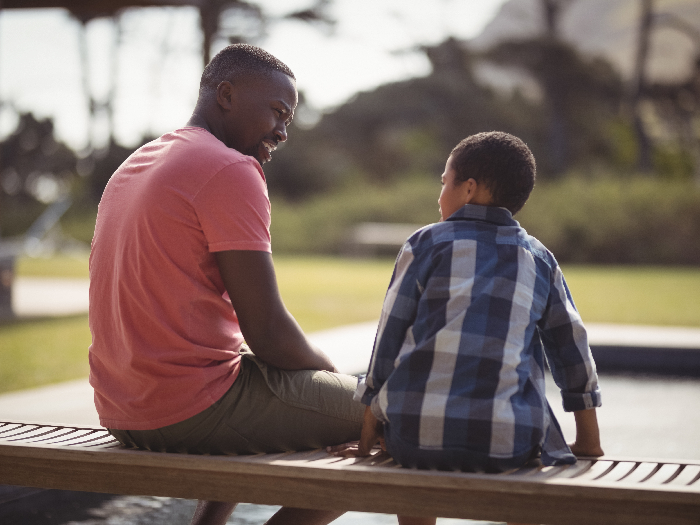 Smiling father talking to son near pool side
