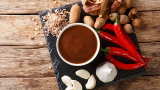 Sweet and sour spicy tamarind chutney with ingredients close-up on a wooden table