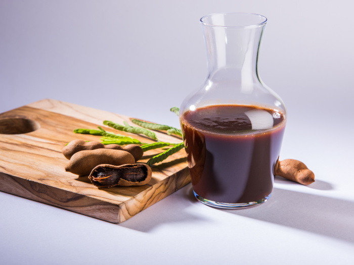 Raw tamarind fruits with sauce or puree in glass jar, imli chutney in Hindi