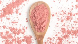 Tart cherry extract on a wooden spoon on a white background