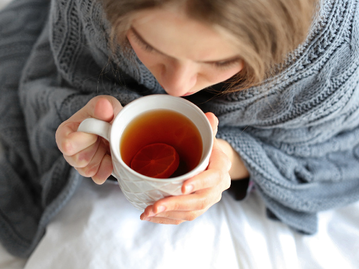 Close up of a woman wearing woolens, holding a cup of hot tea