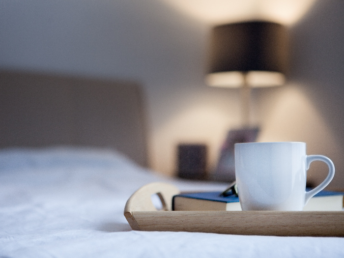 A cup of hot drink and book on a bed