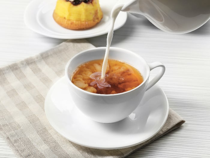 Pouring milk into a cup of black tea