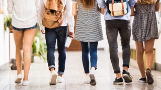 Back view of teenage students walking in school hall