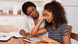 A mother helping stressed teenage daughter with homework